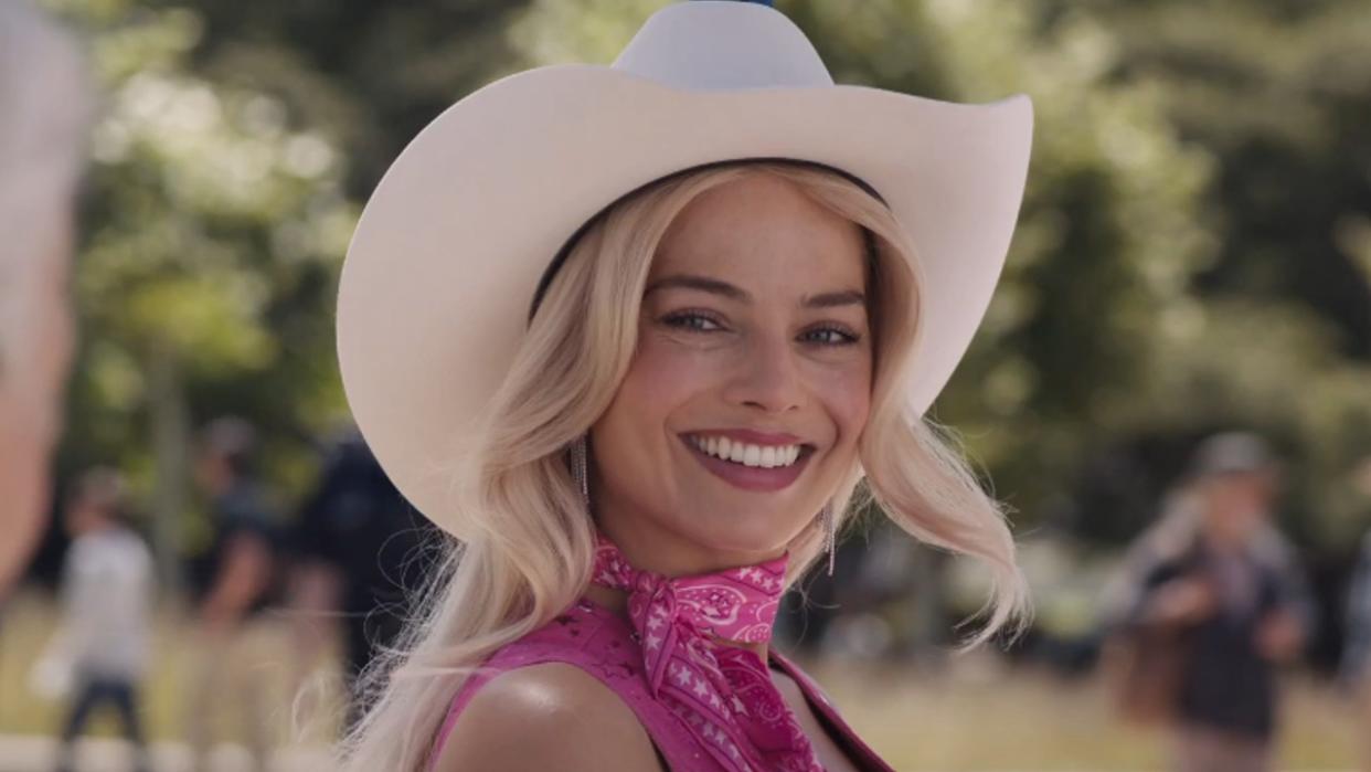  Barbie smiling while wearing a cowgirl hat in Barbie. 