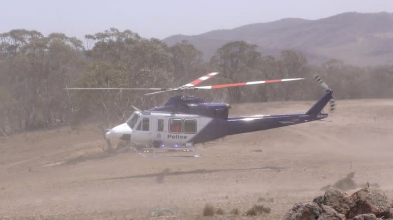 A police helicopter lands as investigations take place into the crash of a C-130 air tanker plane after dropping fire retardant, in this January 24, 2020 still frame obtained from social media video, in Snowy Mountains, New South Wales, Australia