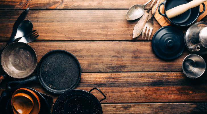 A variety of kitchen supplies are displayed on a wooden surface.