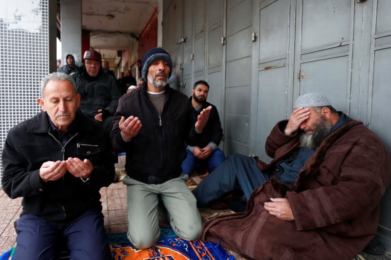 Palestinians perform Friday prayers on a sidewalk as mosques are closed over concerns of the spread of the coronavirus disease, in Ramallah in the Israeli-occupied West Bank