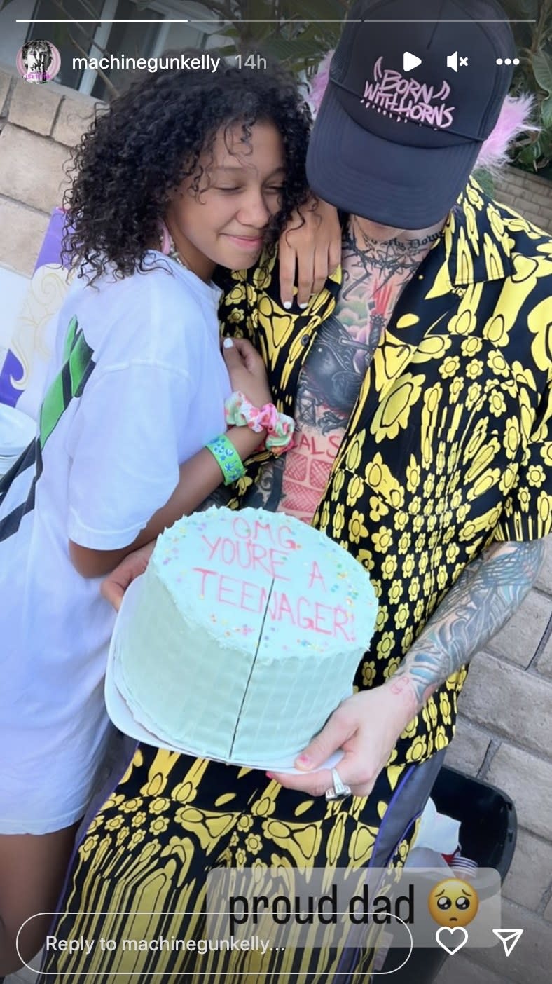 Casie poses with MGK while he holds a large cake