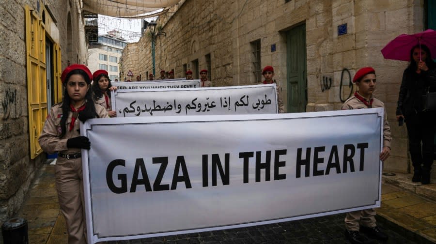 <sub><em>Palestinian scouts hold signs in solidarity with Palestinians in the Gaza Strip calling to end the Israel-Hamas war, near the Church of the Nativity, traditionally believed to be the birthplace of Jesus, on Christmas Eve in the West Bank city of Bethlehem, Sunday, Dec. 24, 2023. Bethlehem is having a subdued Christmas after officials in Jesus’ traditional birthplace decided to forgo celebrations due to the Israel-Hamas war. (AP Photo/Mahmoud Illean)</em></sub>