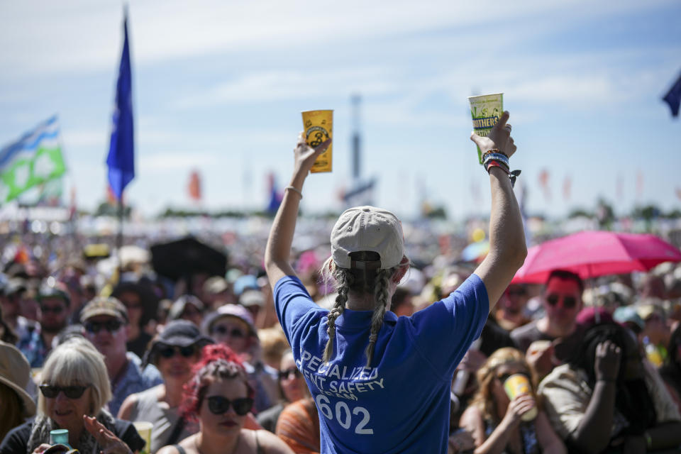 Una miembro del equipo especializado en seguridad de eventos ofrece agua a los asistentes al festival antes de la presentación de The Last Dinner Party en el Festival de Glastonbury en Worthy Farm, Somerset, Inglaterra, el sábado 29 de junio de 2024. (Scott A Garfitt/Invision/AP)