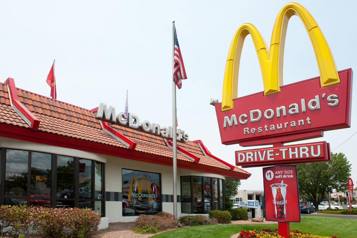 Exterior of a McDonald's in Albuquerque, New Mexico with sign in the foreground with a shopping center in the distant background