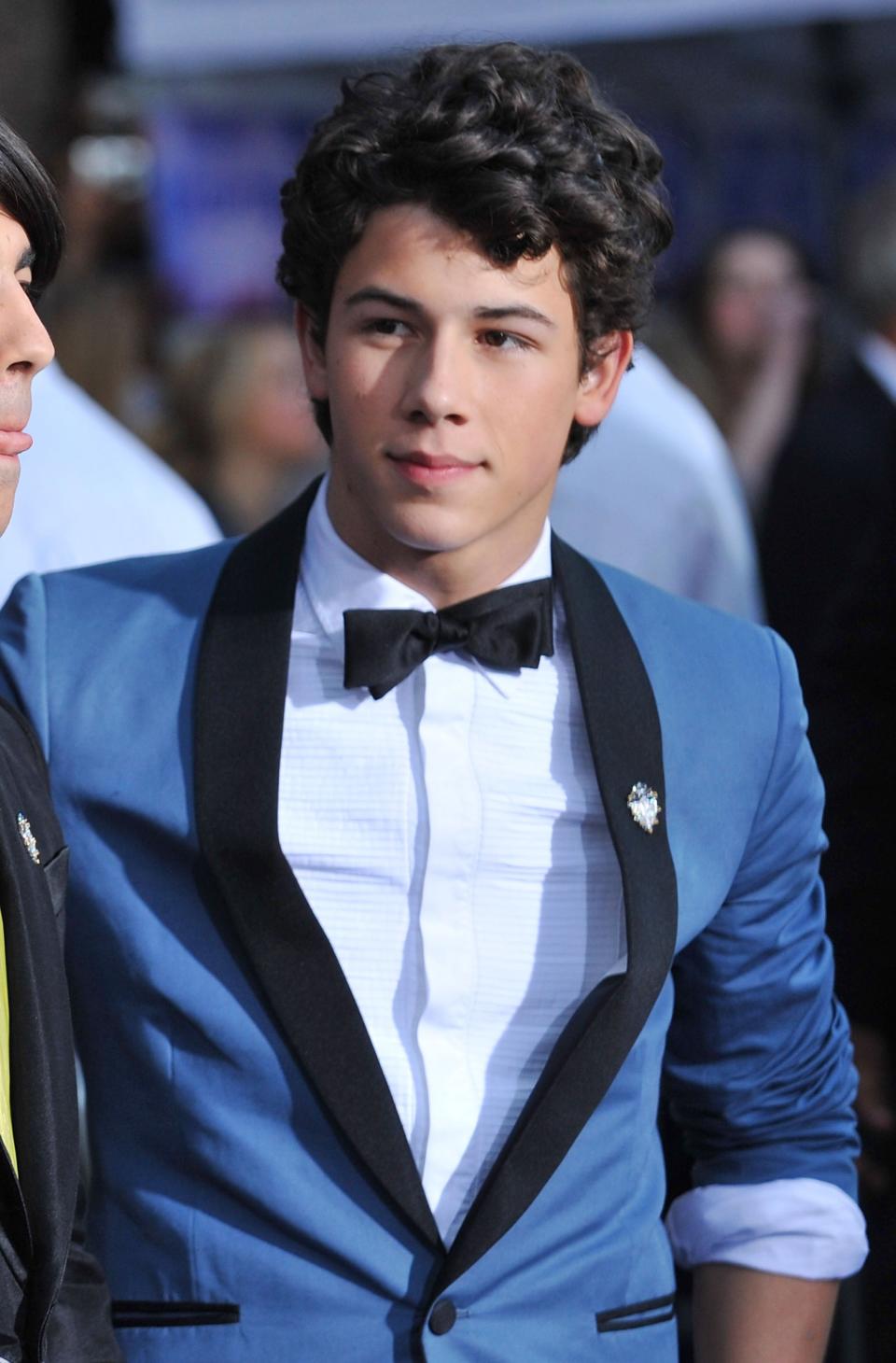 A younger Nick Jomas in a tuxedo with bow tie and lapel pin