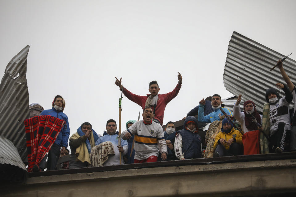 Rioting inmates protest from the roof of the Villa Devoto prison as they protest against authorities who they say are not doing enough to prevent the spread of coronavirus inside the jail in Buenos Aires, Argentina, Friday, April 24, 2020. (AP Photo/Natacha Pisarenko)