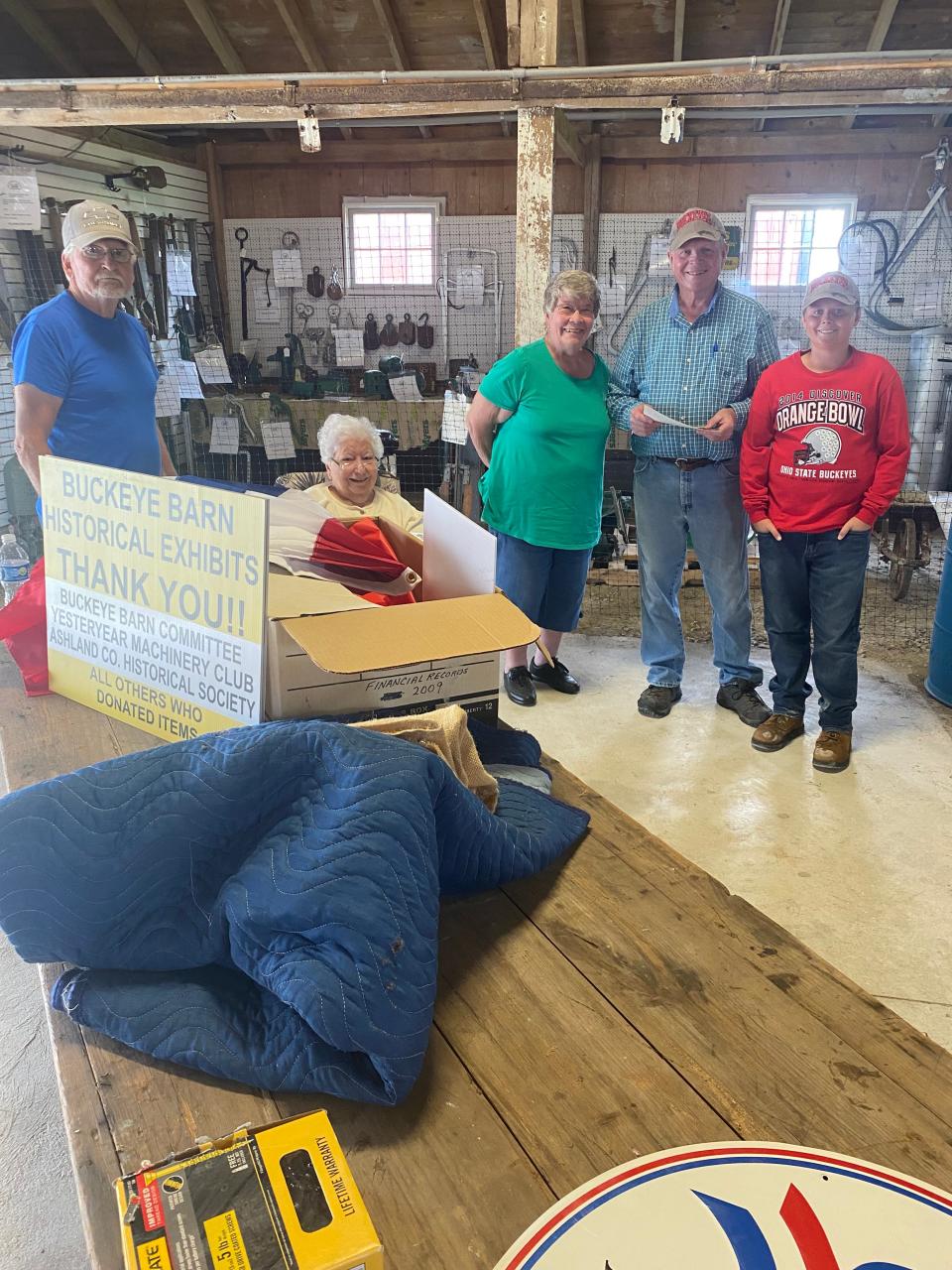Bill Nolan, left, Edna Cox, Susie Stake, Dave Snyder and Colt Snyder put pictures and other things to exhibit for the display cases in the Buckeye Barn at the Ashland County Fairgrounds for the Yesteryear Show. Items are planned to be added for the fair in September.