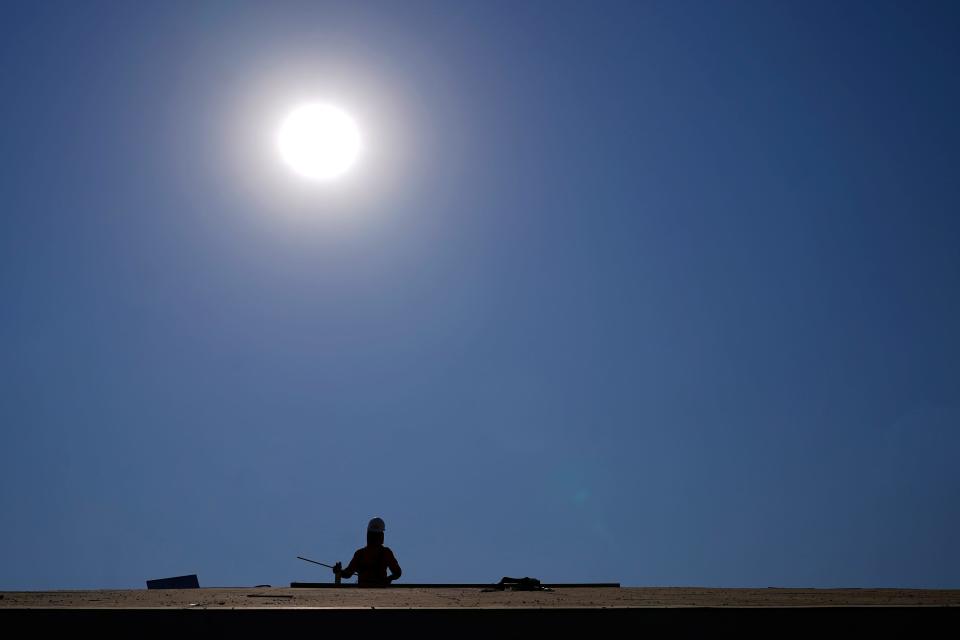 A roofer works in a housing development while the sun beats down on him during a June 2021 heat wave in Phoenix.