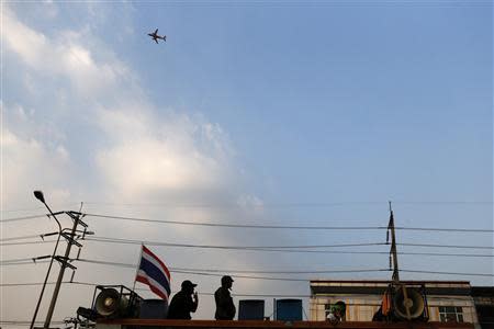 An airplane takes off as Thai anti-government protesters stand on their truck during a gunfight between supporters and opponents of Thailand's government near Laksi district office in Bangkok February 1, 2014. REUTERS/ Nir Elias