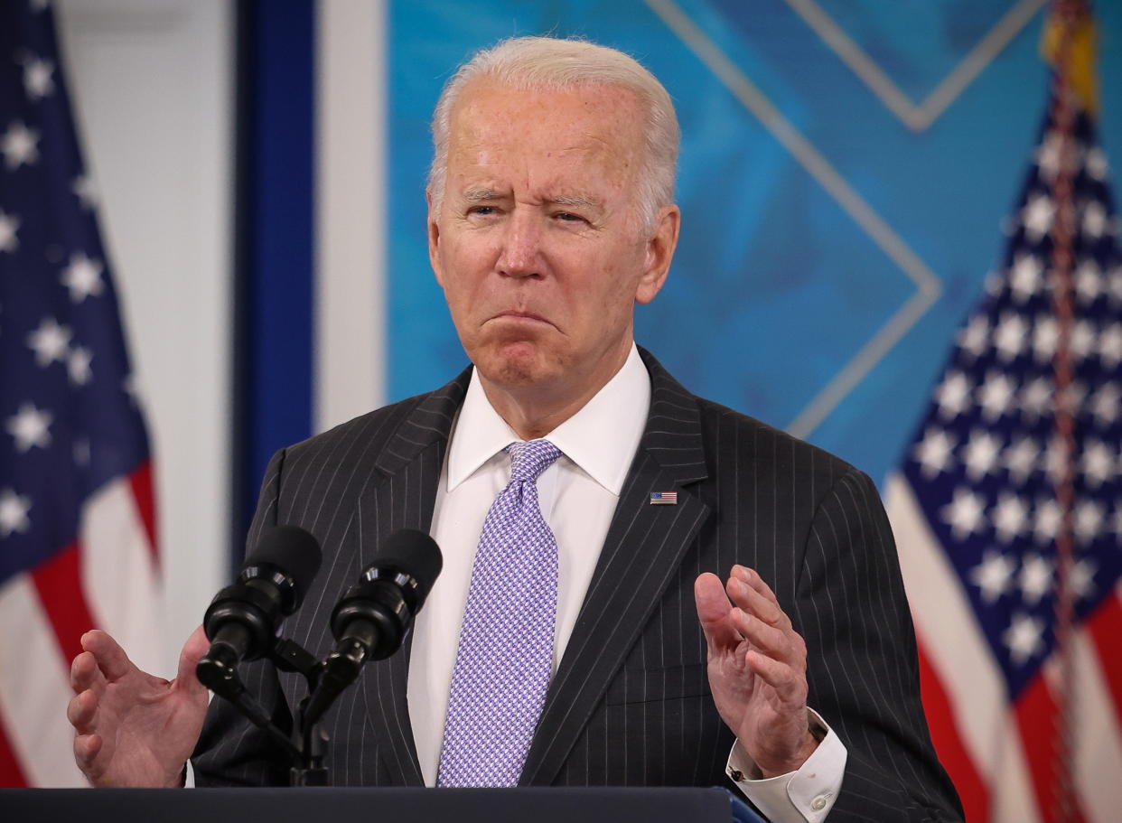 President Biden stands at a podium with American flags in the background while speaking at the White House.