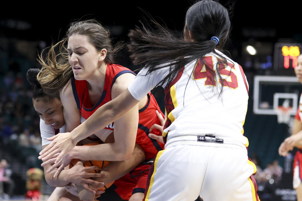 Southern California guards JuJu Watkins, left, and Kayla Padilla (45) attempt to steal the ball from Arizona guard Helena Pueyo, center, during the first half of an NCAA college basketball game in the quarterfinal round of the Pac-12 tournament Thursday, March 7, 2024, in Las Vegas. (AP Photo/Ian Maule)