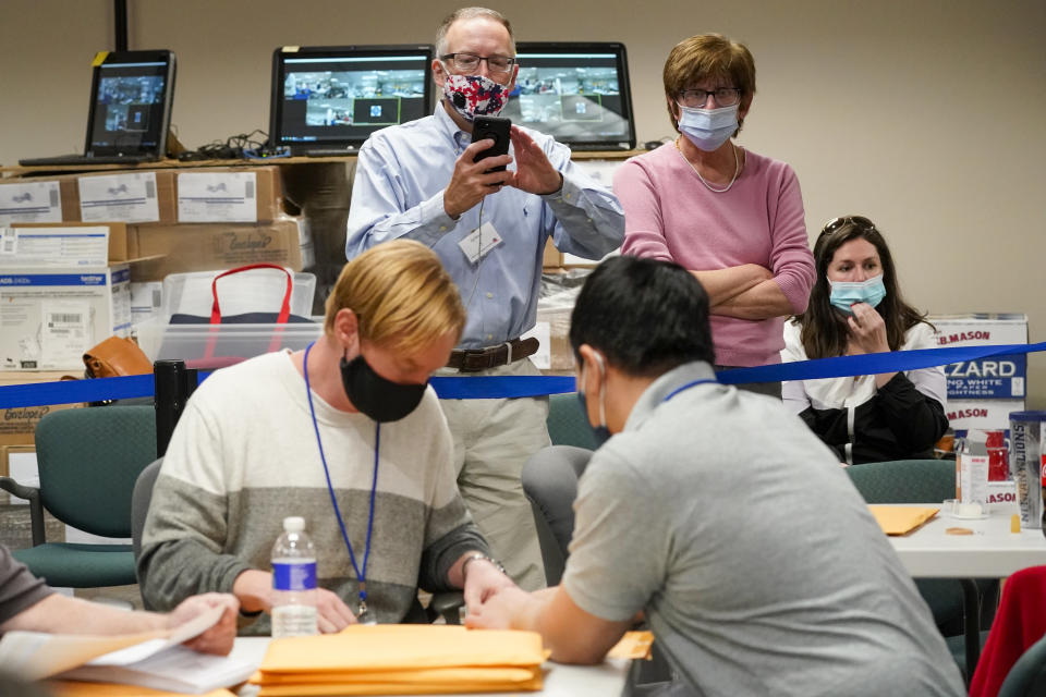 Republican canvas observer Ed White, center, and Democratic canvas observer Janne Kelhart, watch as Lehigh County workers count ballots as vote counting in the general election continues, Friday, Nov. 6, 2020, in Allentown, Pa. (AP Photo/Mary Altaffer)