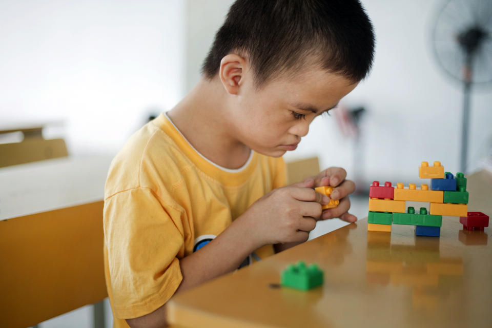 In this photo taken on Wednesday, Aug. 8, 2012, Le Trung Hong Phuc, 9, plays with colored blocks at a rehabilitation center in Danang, Vietnam. The children were born with physical and mental disabilities that the center's director says were caused by their parents' exposure to the chemical dioxin in the defoliant Agent Orange. On Thursday, the U.S. for the first time will begin cleaning up leftover dioxin that was stored at the former military base that's now part of Danang's airport. (AP Photo/Maika Elan)