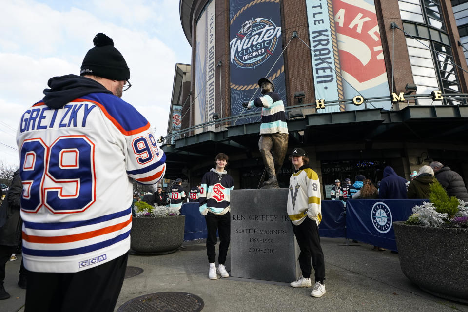 Fans take a photo with the statue of former Seattle Mariners player Ken Griffey Jr. outside of T-Mobile Park before the NHL Winter Classic hockey game between the Seattle Kraken and the Vegas Golden Knights, Monday, Jan. 1, 2024, in Seattle. (AP Photo/Lindsey Wasson)