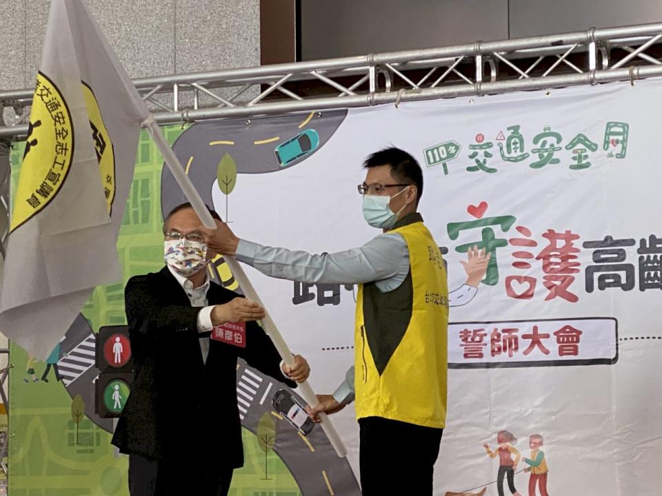 交通部政務次長陳彥伯(左)19日在「路老師宣誓大會」上授旗給「路老師」代表。(吳琍君 攝)