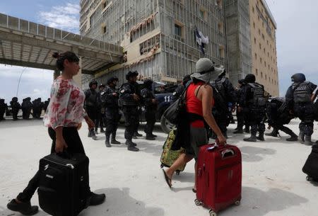 Stranded tourists walk past police officers towards a Mexican Army plane, outside the international airport in San Jose del Cabo after Hurricane Odile hit Baja California, September 19, 2014. REUTERS/Henry Romero