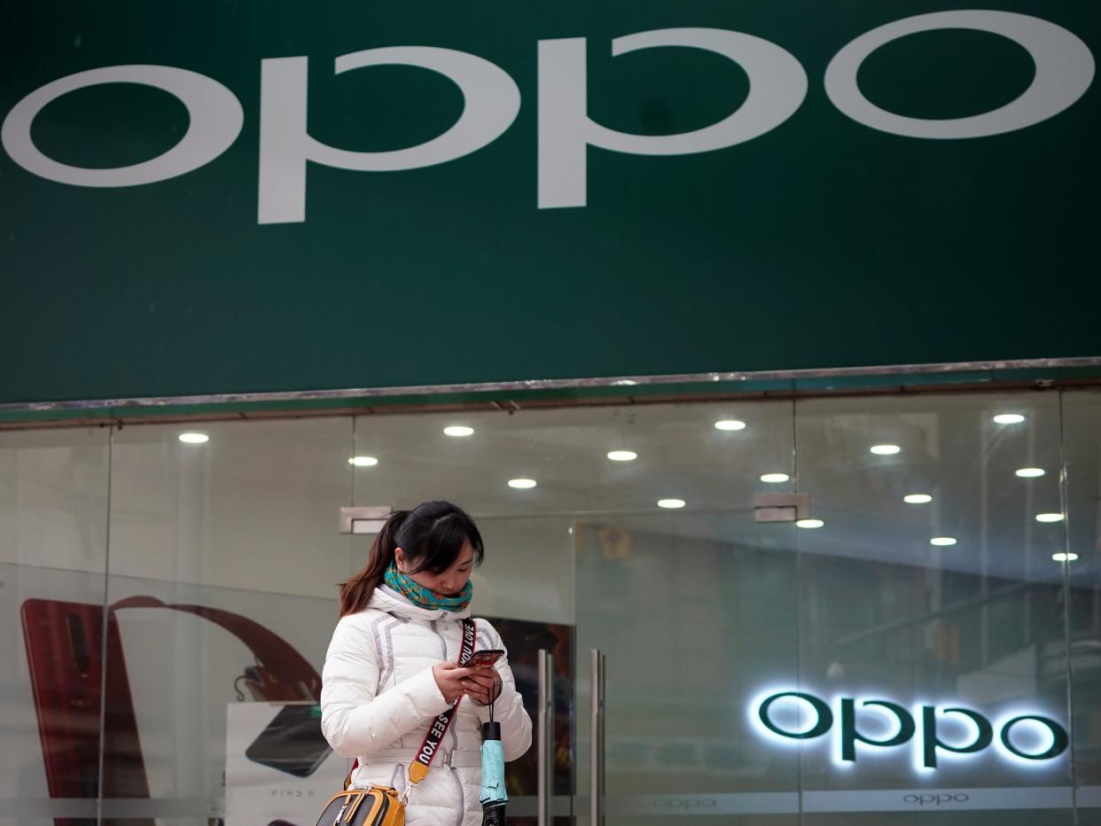 FILE PHOTO: A woman walks by an Oppo logo at a shopping mall in Shanghai, China February 21, 2019. REUTERS/Aly Song