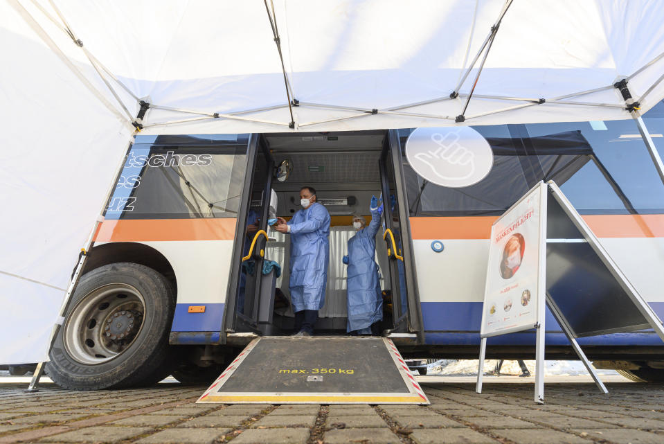 Medical staff prepare a bus, containing a so-called rolling vaccination centre for a the test run in Grosshartmannsdorf, Germany, Sunday, Feb. 21, 2021. Mobile vaccination centers will be used to vaccinate people against the coronavirus and the COVID-19 disease in three municipalities of German federal state Saxony. (Robert Michael/dpa via AP)