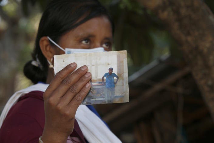 Basilia Tepetitlan holds a photo of her husband who was murdered along with nine other musicians including a 15-year-old boy by a criminal gang that burned them and sent their vehicles off a cliff in Alcozacan, Guerrero state, Mexico, Thursday, April 29, 2021. The community got scholarships for the victims' orphaned children and homes for the widows like Tepetitlan. (AP Photo/Marco Ugarte)