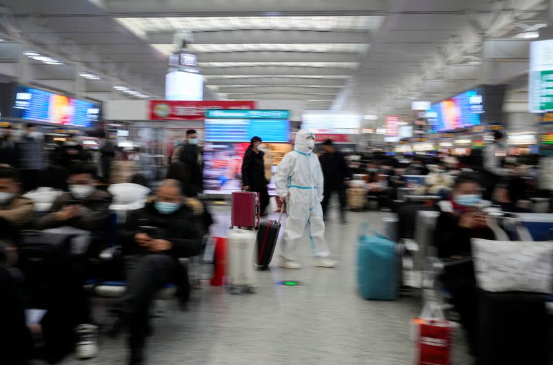 Una mujer con equipo de protección personal (EPP) camina con su equipaje en la estación de tren de Hongqiao de Shanghái durante el ajetreo anual de viajes de la Fiesta de la Primavera antes del Año Nuevo Lunar chino, mientras continúa el brote de la enfermedad por coronavirus (COVID-19), en Shanghái, China