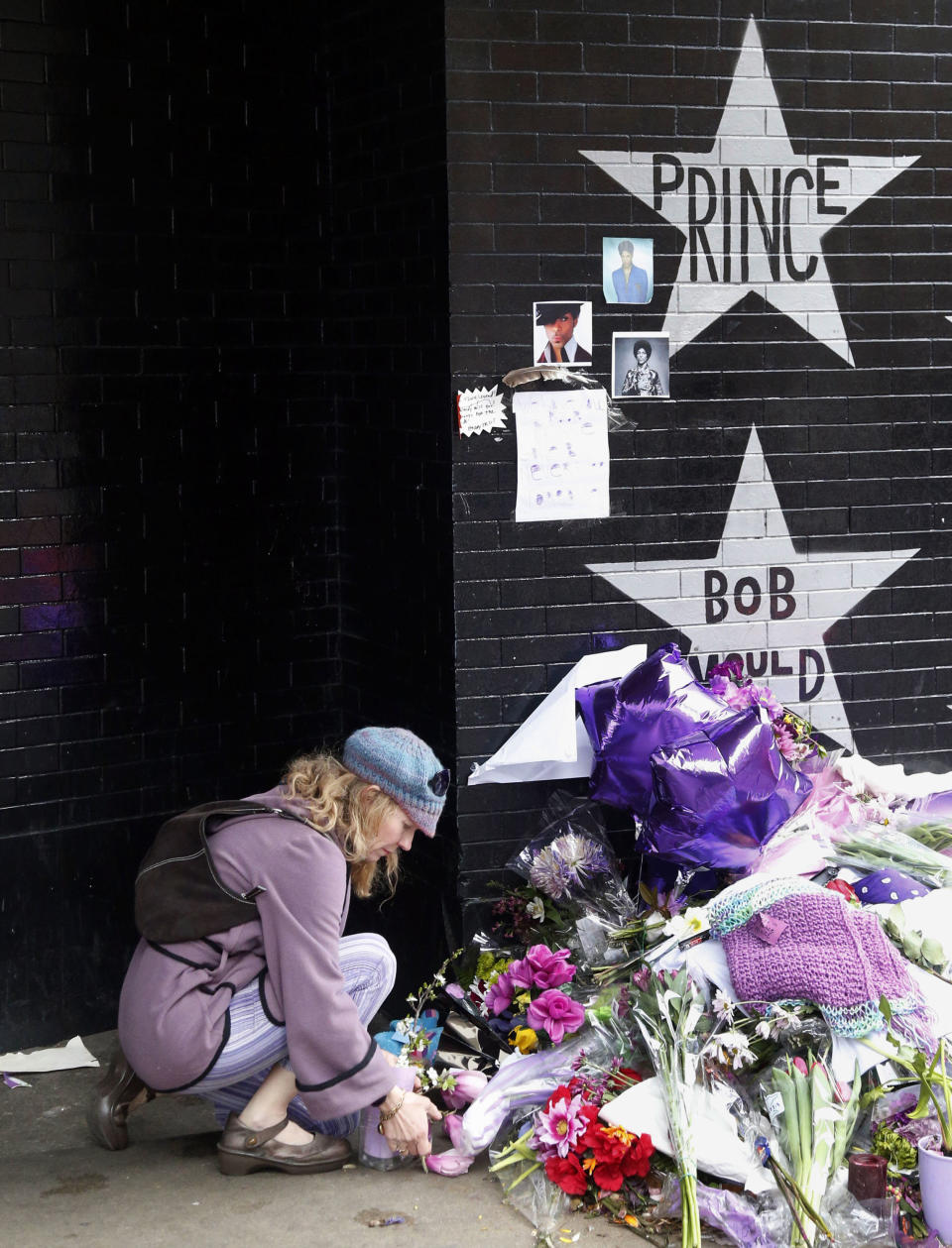 FILE - In this April 22, 2016, file photo, a woman places flowers at a memorial at First Avenue in Minneapolis where pop super star Prince often performed. The one-year anniversary of Prince's death from an overdose will be marked April 21. (AP Photo/Jim Mone, File)