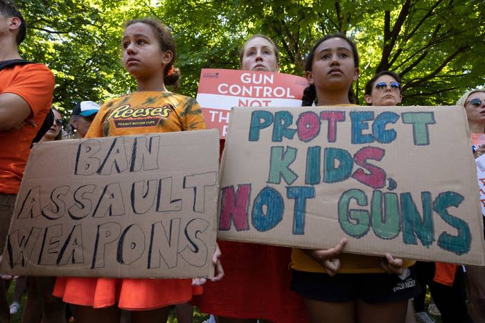 Young children at a protest holding signs that says "protect kids, not guns" and "ban assault weapons"