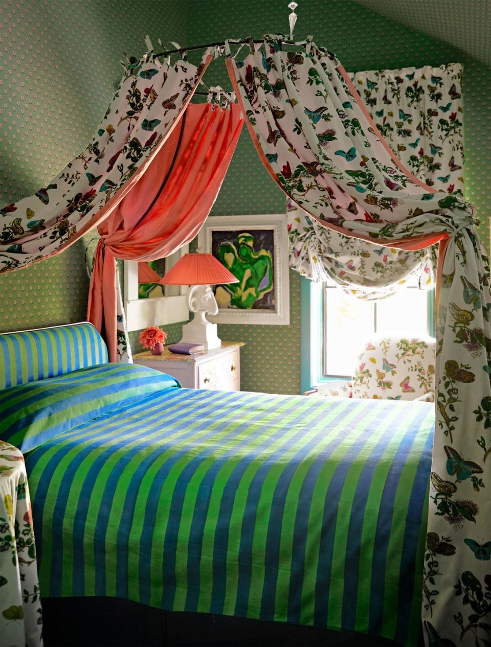 boho bedroom with canopy, spotted wallpaper, french club chair, and fanciful bed curtains