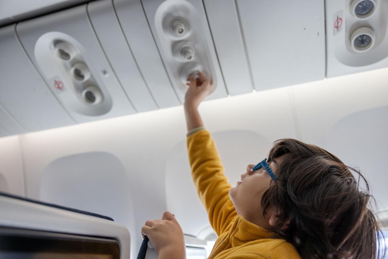 Multiracial boy adjusting the fan in a commercial airplane