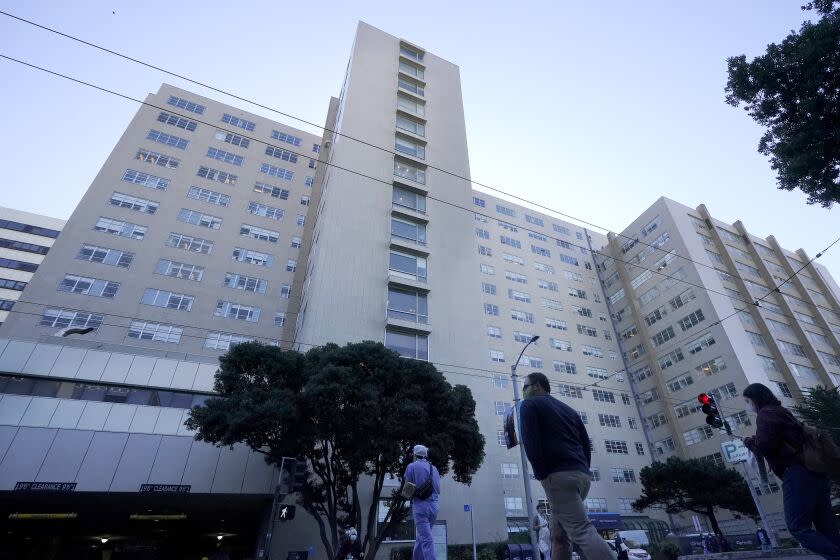 FILE - People cross the street in front of a University of California at San Francisco medical center in San Francisco on Nov. 30, 2020. A prominent California medical school has apologized for conducting unethical experimental medical treatments on 2,600 incarcerated men in the 1960s and 1970s. (AP Photo/Jeff Chiu, File)