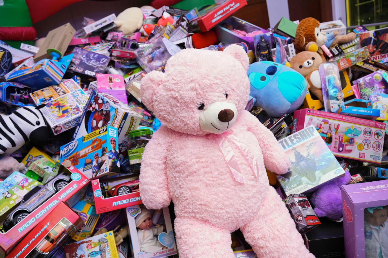  A large pink stuffed bear on top of a pile of toys. 