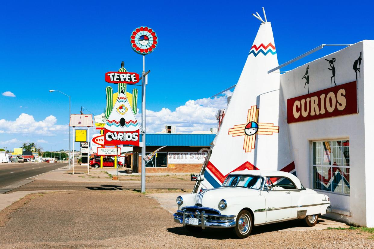 white vintage car in front of tepee curios