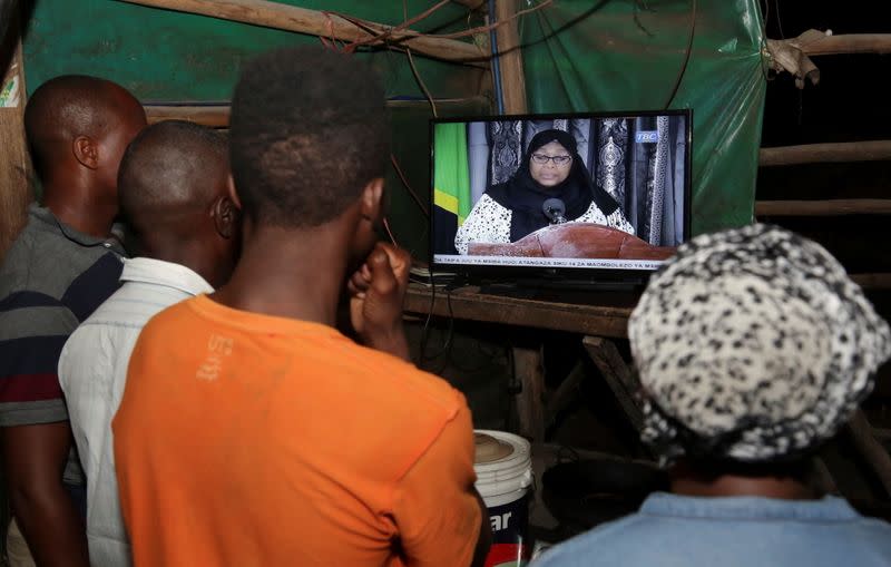 Residents watch the television announcement of the death of Tanzania's President John Magufuli, addressed by Vice President Samia Suluhu Hassan in Dar es Salaam