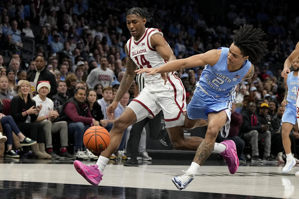 Oklahoma forward Jalon Moore and North Carolina guard Elliot Cadeau chase a loose ball during the first half of an NCAA college basketball game Wednesday, Dec. 20, 2023, in Charlotte, N.C. (AP Photo/Chris Carlson)