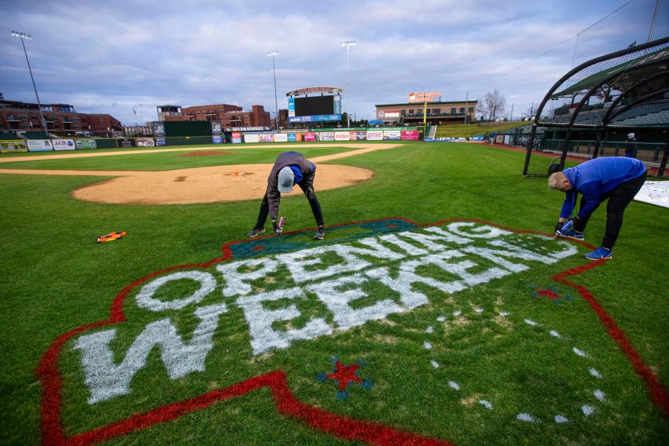 Assistant grounds keeper Jace Coppoc, left, and head grounds keeper Jario Rubio paint the South Bend Cubs opening weekend logo behind home plate Wednesday, April 6, 2022 at Four Winds Field in South Bend. Rubio said they will use around 15 cans of spray paint for the temporary logo and will hand paint the permanent one later this season. The South Bend Cubs open the 2022 season vs. the Quad Cities River Bandits Friday at 7:05 p.m. and play Saturday and Sunday as well. The club hits the road next weekend and returns for a 6-game homestead on April 19. 