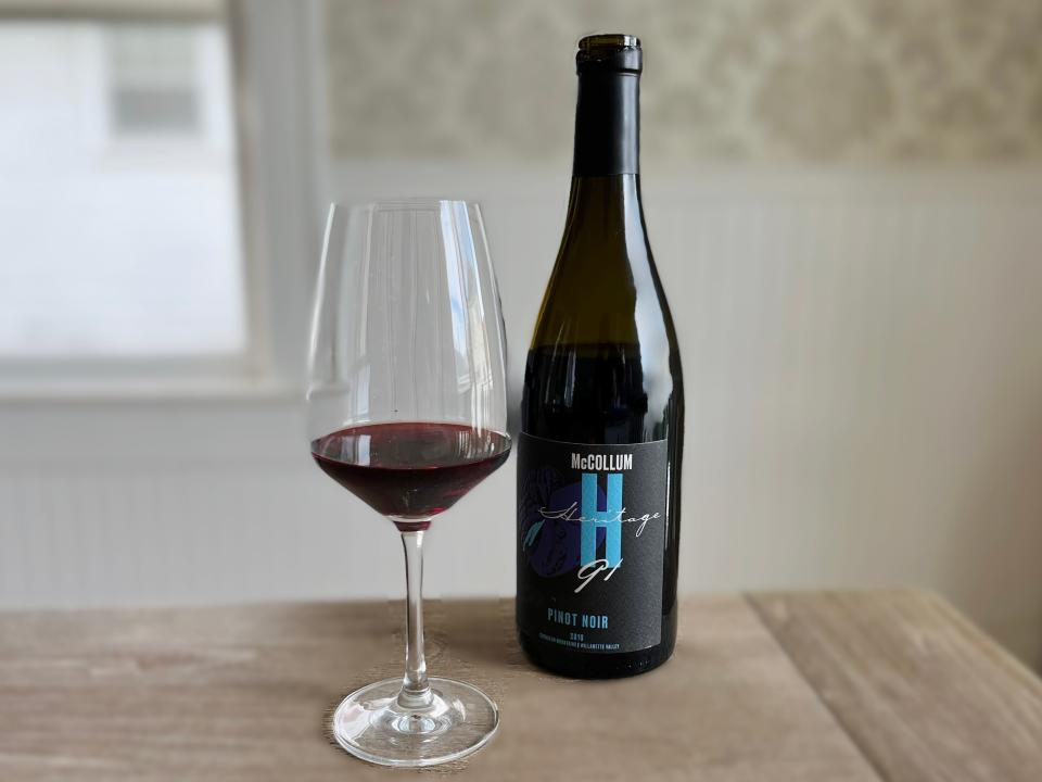 A glass of McCollum Heritage 91 Pinot Noir sits next to the bottle on the table.