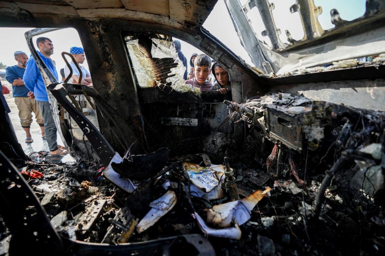 People inspect the site where World Central Kitchen workers were killed in Deir al-Balah, Gaza. (AP Photo/Abdel Kareem Hana - image credit)