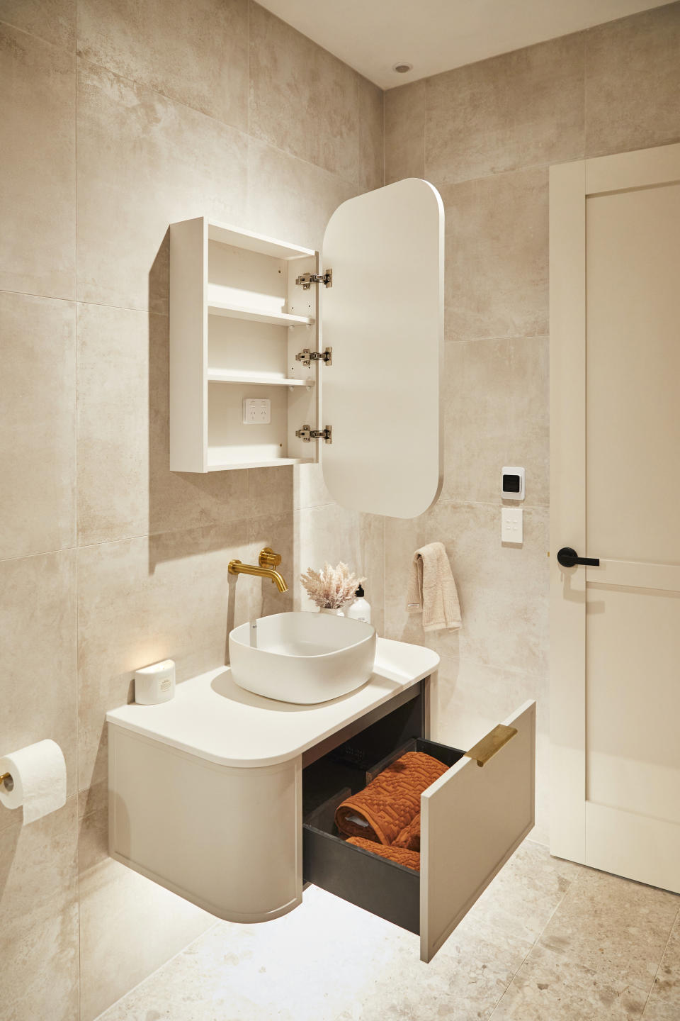 A close up shot of the vanity, with an open drawer and open cupboard above it. 