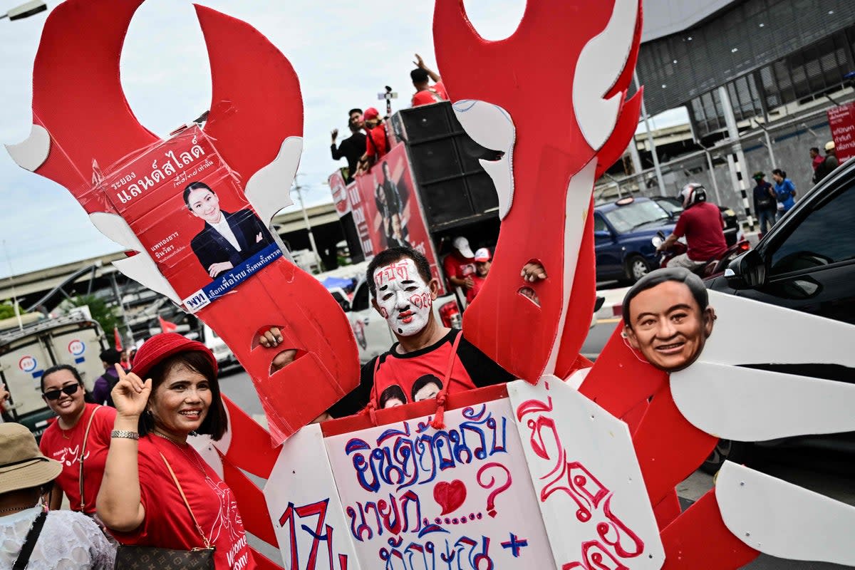 Supporters of Thaksin Shinawatra hold placards as they wait outside Bangkok’s Don Mueang airport (AFP/Getty)