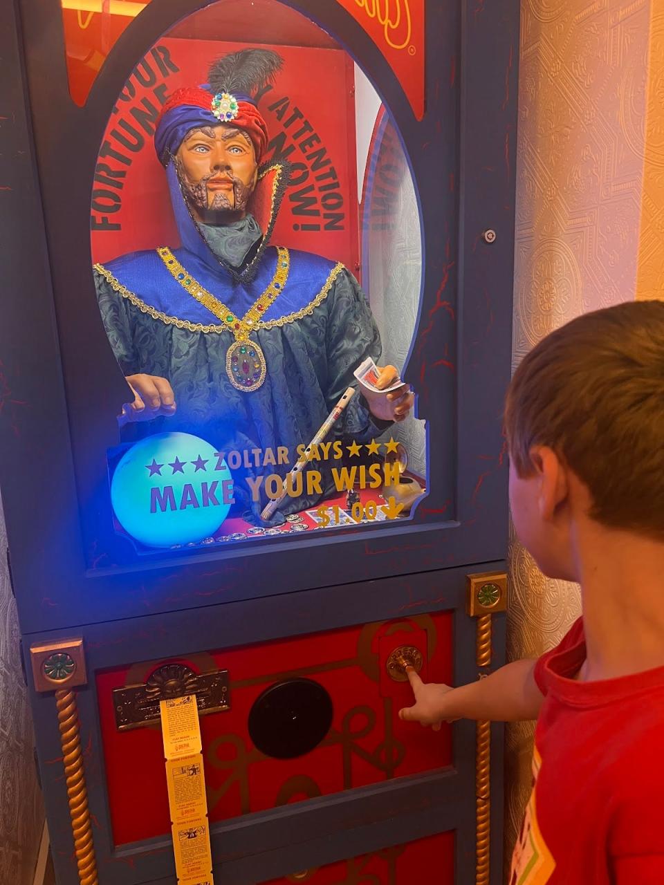 kid pressing a button on a zoltar machine in the big suite at the graduate hotel in nyc