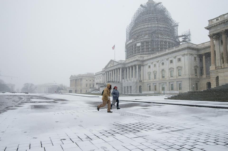 People run through the snow past the US Capitol in Washington, DC, on January 22, 2016. Thousands of flights were cancelled and supermarket shelves were left bare Friday as millions of Americans hunkered down for a winter storm expected to dump historic amounts of snow in the eastern United States.