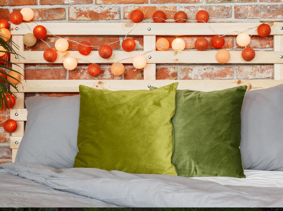 diy headboard with a wood pallet frame and string lights behind a bed