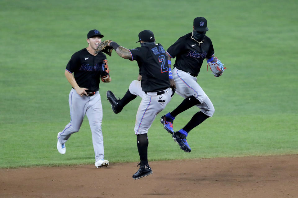 Miami Marlins shortstop Jonathan Villar (2) and center fielder Monte Harrison, right, celebrate after defeating the Baltimore Orioles 2-1 in the second game of a doubleheader, Wednesday, Aug. 5, 2020, in Baltimore. Marlins' Corey Dickerson, left, looks on. (AP Photo/Julio Cortez)