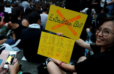 A woman holds placards as she attends a rally in support of demonstrators protesting against proposed extradition bill with China, in Hong Kong