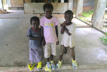 A supplied image shows local children, wearing make-shift shoes, standing in a dilapidated building at the former Bougainville Copper Limited's (BCL) Panguna mining operation located on the Pacific Ocean island of Bougainville, Papua New Guinea, August 25, 2014. Picture taken August 25, 2014. Renzie Duncan/Handout via REUTERS
