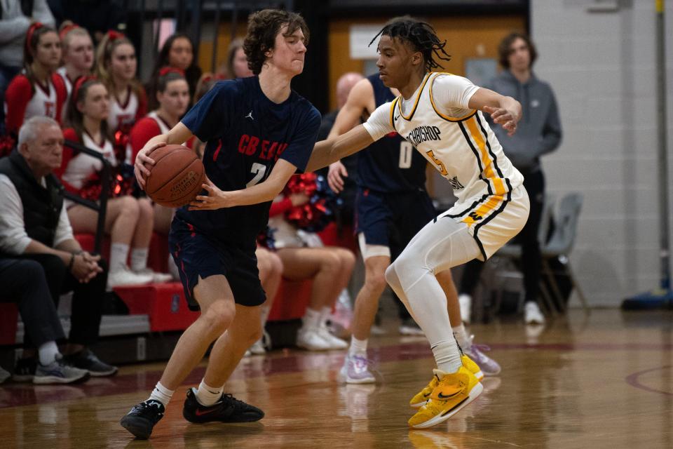 Central Bucks East senior Kyle Berndt looks to pass as Archbishop Wood junior Josh Reed applies defensive pressure during the Vikings' 61-37 win in a PIAA Class 6A first-round state playoff game.