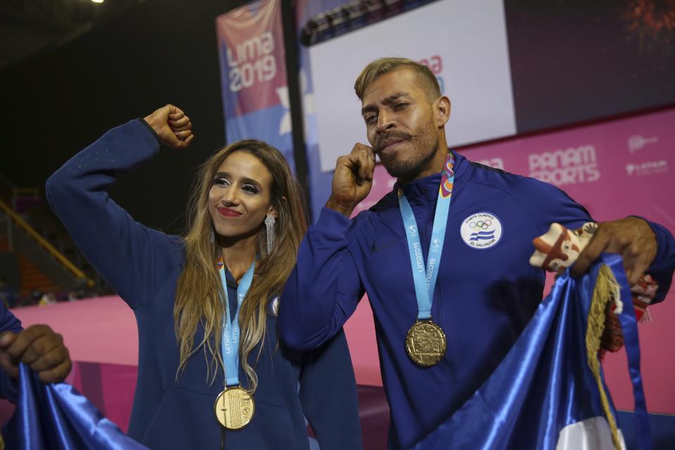 Gold medalist Paulina Zamora, left, and gold medalist Yuri Rodriguez, both of El Salvador, celebrate after the medal ceremony for the women's fitness and men's classic competitions at the debut of bodybuilding as an official sport at the Pan American Games in Lima, Peru, Saturday, Aug.10, 2019. (AP Photo/Rodrigo Abd)
