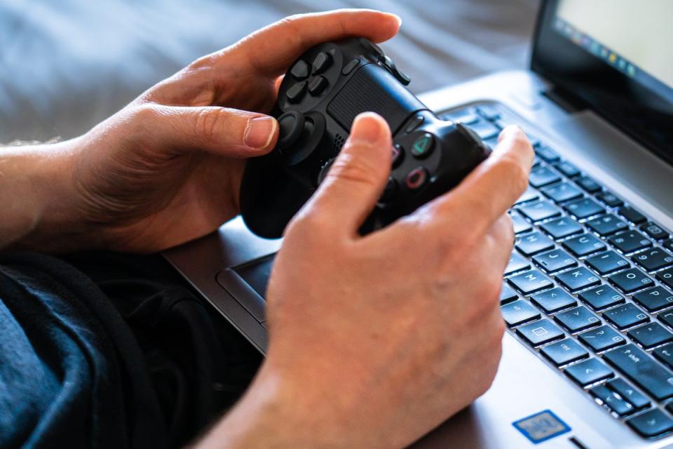 Someone gaming on a laptop with a DualShock pad (Castorly Stock / Pexels)