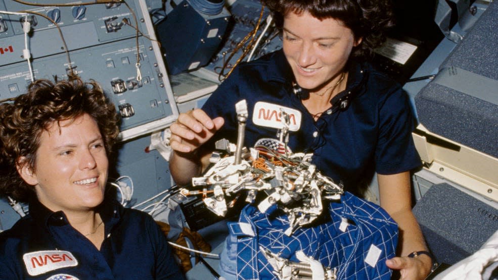  two women astronauts in space shuttle holding hardware 