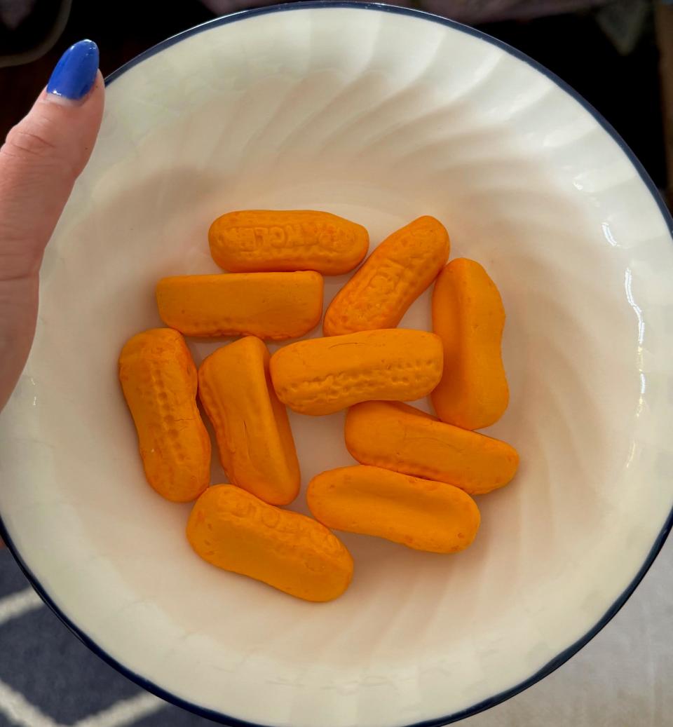 Hand holding a bowl with orange, oval-shaped crackers imprinted with "CIRCUS"