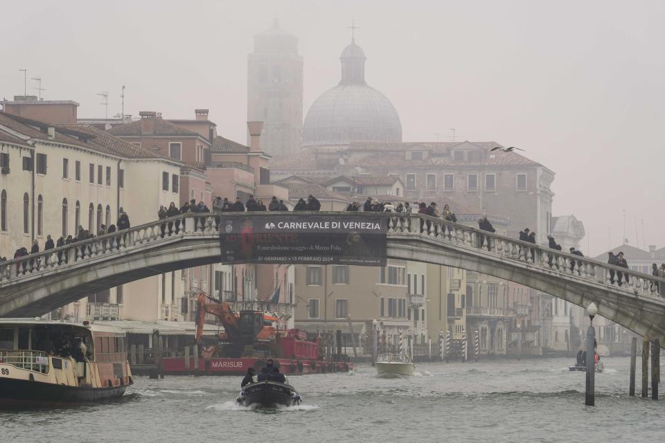 A banner reading in Italian 'Carnival of Venice, to the East, the amazing journey of Marco Polo' is displayed on a bridge during the opening day of the Venice Carnival, in Venice, Italy, Saturday, Jan. 27, 2024. Venice is marking the 700th anniversary of the death of Marco Polo with a yearlong series of commemorations, starting with the opening of Carnival season honoring one of the lagoon city's most illustrious native sons. (AP Photo/Luca Bruno)